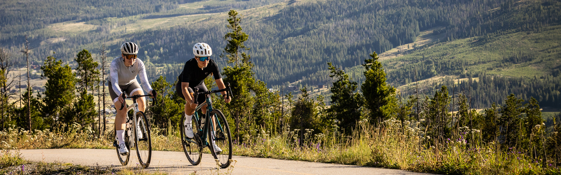 two cyclists riding in PEARL iZUMi kits, with forestry scenery